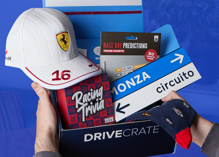 An open DriveCrate box with a racing cap, trivia book and Monza sign