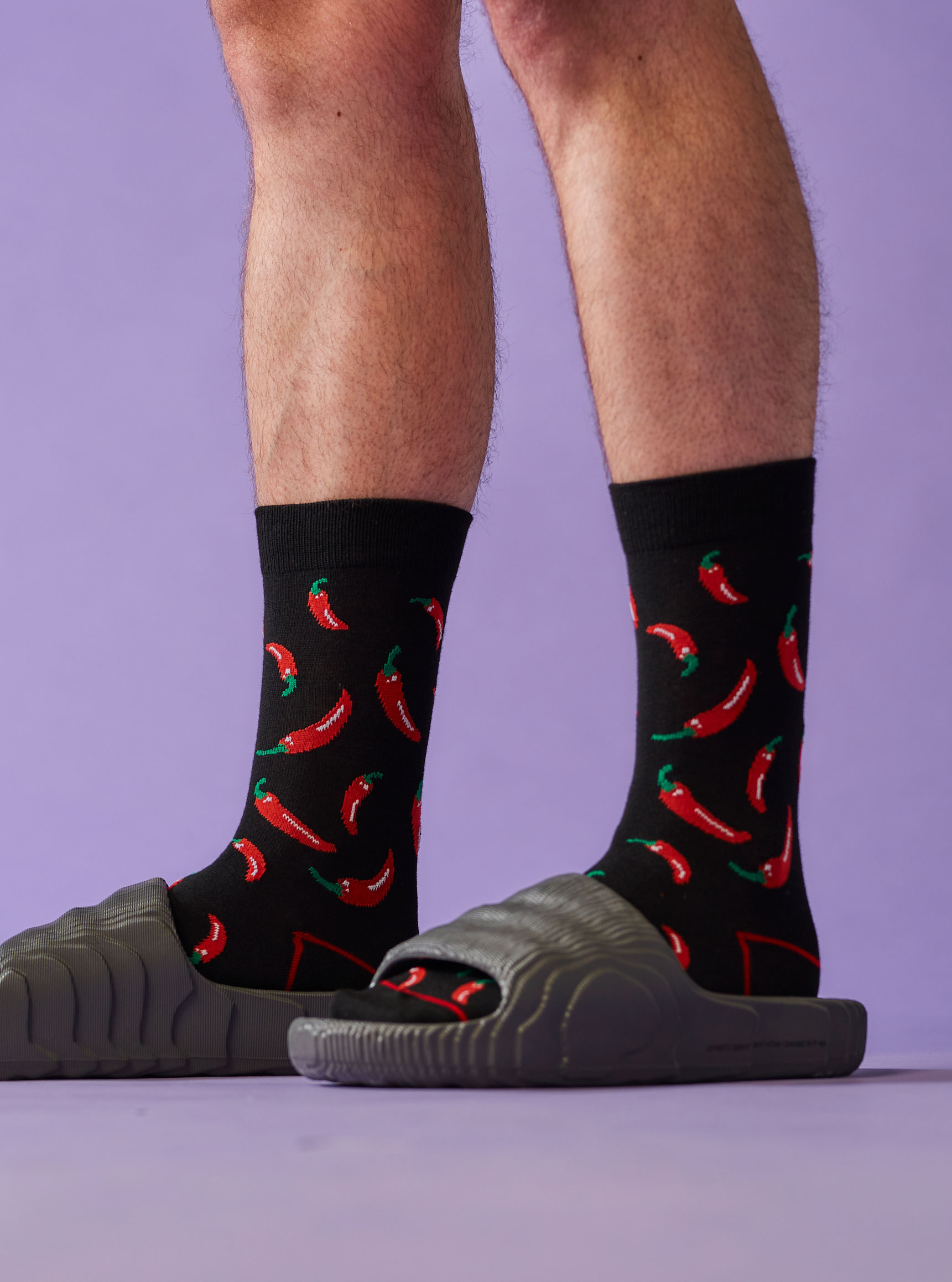 Legs in black PostSox socks with a red chilli pattern